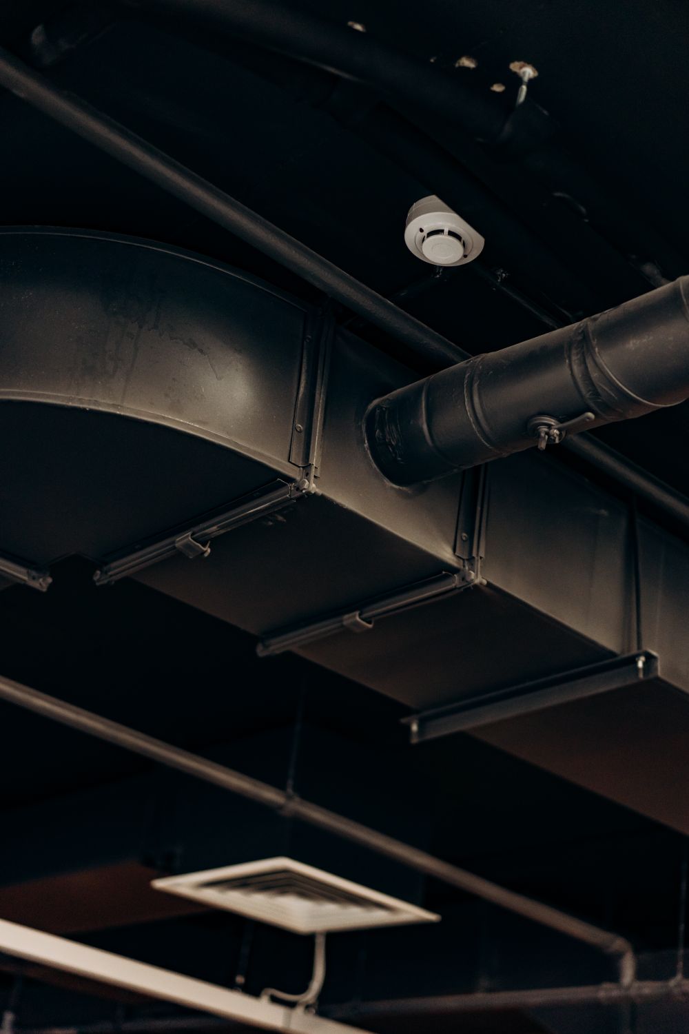 Exposed metal ventilation ducts and an air vent above a room
