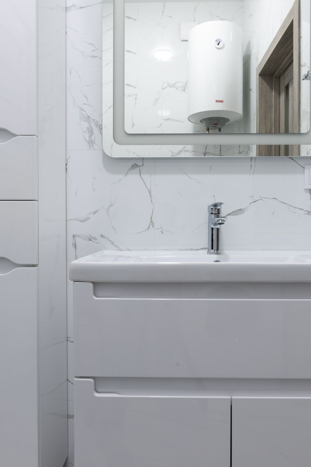 Bathroom sink and mirror reflecting a wall-mounted water heater